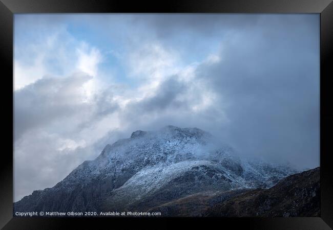 Stunning moody dramatic Winter landscape image of snowcapped Tryfan mountain in Snowdonia with stormy weather brooding overhead Framed Print by Matthew Gibson