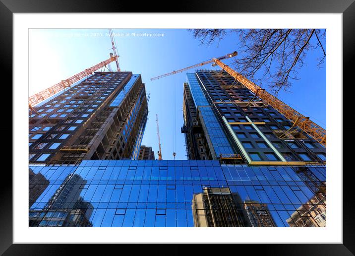The glass facade, a reflection of the blue sky and cranes near a modern concrete building under construction. Framed Mounted Print by Sergii Petruk