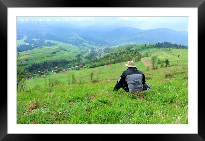 Traveler's view of the picturesque landscape of the Carpathian Mountains and the village in the valley, shrouded in mist. Framed Mounted Print by Sergii Petruk