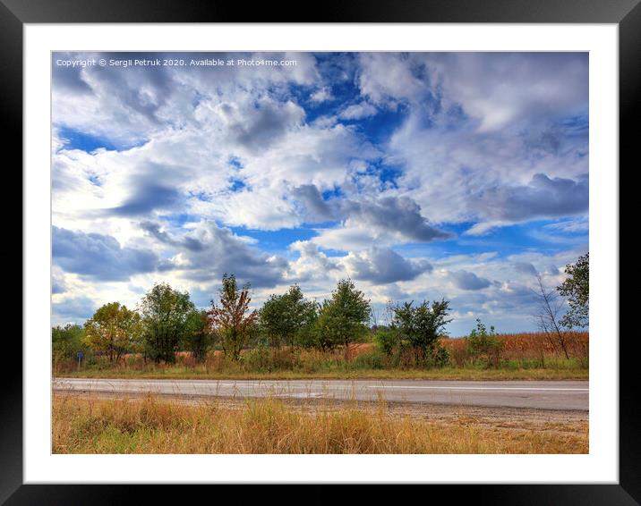 The landscape of the road against the blue sky and the gathering thunderstorm clouds on a summer day. Framed Mounted Print by Sergii Petruk