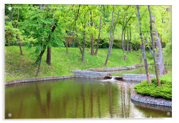 A forest lake surrounded by trees in a beautiful park, framed by cobblestone shores in the rays of soft light. Acrylic by Sergii Petruk