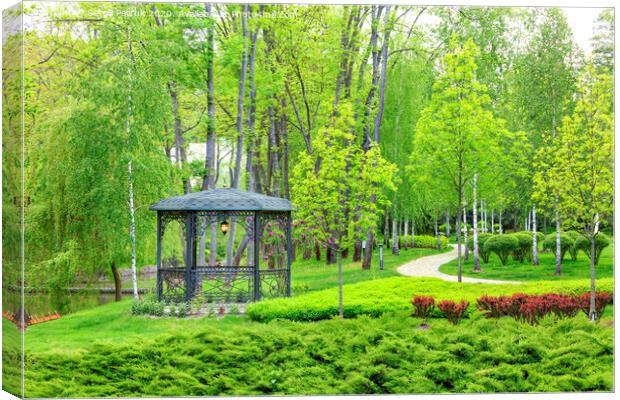 Openwork metal arbor with forged elements surrounded by beautiful spring park with landscape design. Canvas Print by Sergii Petruk
