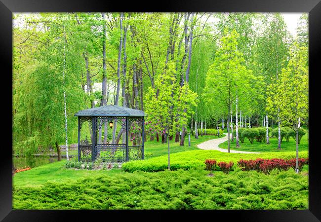 Openwork metal arbor with forged elements surrounded by beautiful spring park with landscape design. Framed Print by Sergii Petruk
