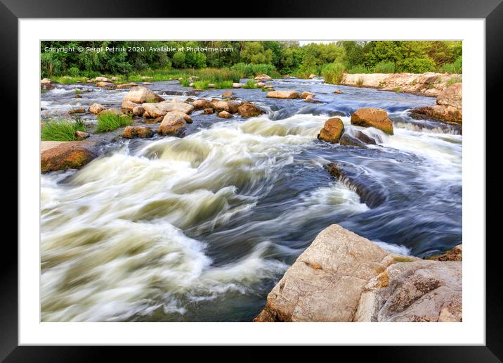 The rapid flow of the river in the blur, rocky shores, boulders and rapids, bright green vegetation on the other side of the shore. Framed Mounted Print by Sergii Petruk