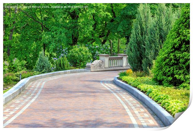 Walkway paved with tiles in a beautiful park, framed by different bushes and flowers, in soft rays of morning light. Print by Sergii Petruk