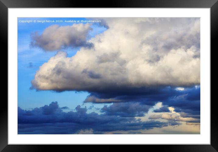 Storm clouds gather in a pile closing off a blue sky Framed Mounted Print by Sergii Petruk