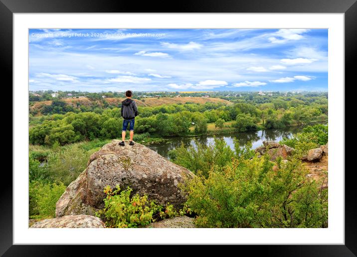 A teenager stands on top of a large stone boulder on the banks of the Southern Bug and looks into the distance. Framed Mounted Print by Sergii Petruk