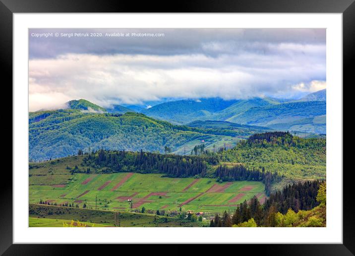 In the valley on the mountainside stretched rectangular agricultural land plots against the backdrop of the picturesque landscape of the Carpathian Mountains, shrouded in mist. Framed Mounted Print by Sergii Petruk