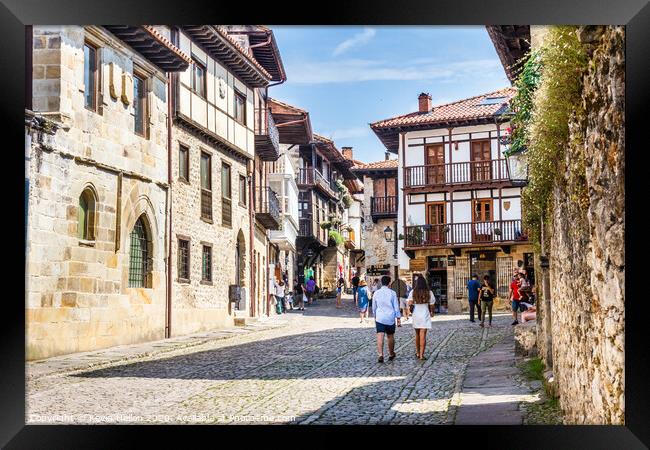 Tourists walking around the town in Santillana, Sp Framed Print by Kevin Hellon