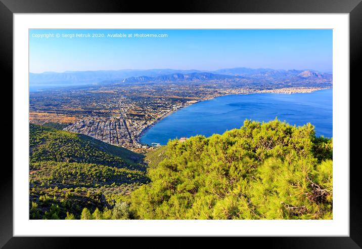 A beautiful fluffy spruce tree with cones under the bright sun against the backdrop of the city of Loutraki and the sea of blue Corinthian Gulf. Framed Mounted Print by Sergii Petruk