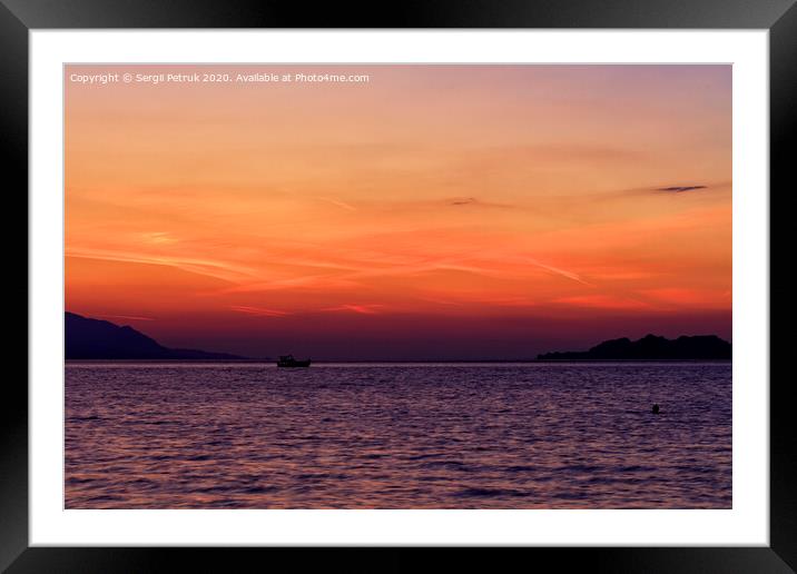 Silhouette of a sea boat running along the horizon of the sea line against the backdrop of a beautiful, vibrant sunset on the Gulf of Corinth. Framed Mounted Print by Sergii Petruk