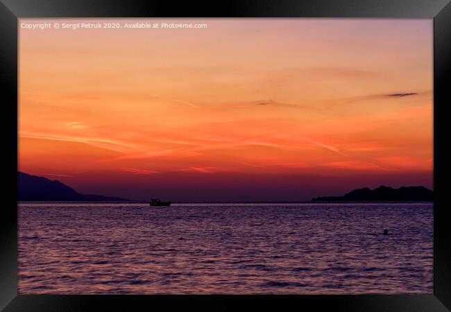 Silhouette of a sea boat running along the horizon of the sea line against the backdrop of a beautiful, vibrant sunset on the Gulf of Corinth. Framed Print by Sergii Petruk