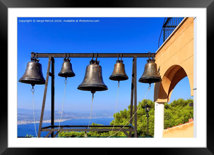 Closeup of bells against a blue sky, mediterranean pine and sea coast in blur, Greece, August 2019. Framed Mounted Print by Sergii Petruk