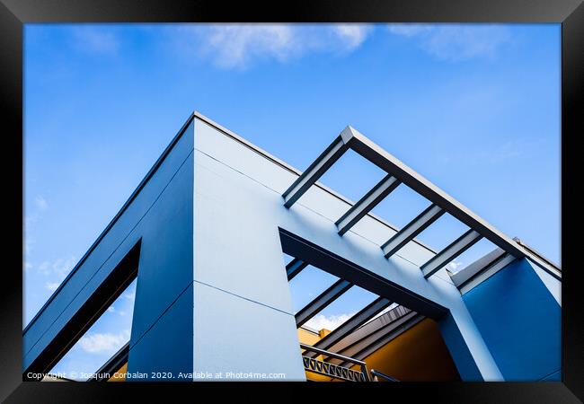 Roof of a blue painted straight design building behind a clear and clear sky at sunset. Framed Print by Joaquin Corbalan
