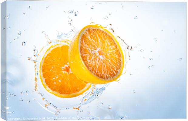 Two halves of orange fruit splashing into clear water. Canvas Print by Przemek Iciak