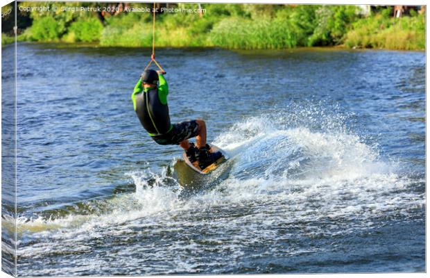 A wakeboarder rushes through the water at high speed along the green bank of the river. Canvas Print by Sergii Petruk