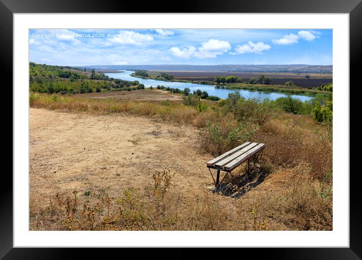 View of a wooden bench on a high river bank on a bright autumn day. Rural autumn landscape. Framed Mounted Print by Sergii Petruk