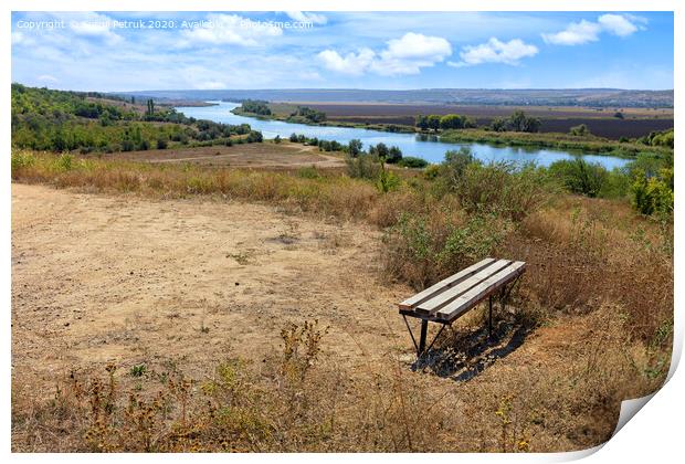 View of a wooden bench on a high river bank on a bright autumn day. Rural autumn landscape. Print by Sergii Petruk