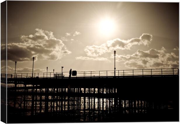 Sepia image of part of Southend Pier shot against the sun, with silhouette of structure and a man on the walkway. Southrnd on Sea, Essex. Canvas Print by Peter Bolton