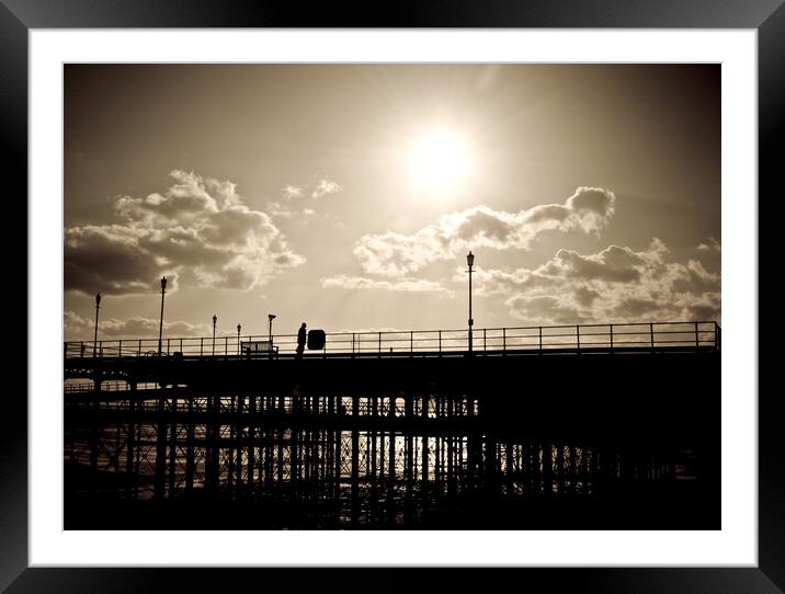 Sepia image of part of Southend Pier shot against the sun, with silhouette of structure and a man on the walkway. Southrnd on Sea, Essex. Framed Mounted Print by Peter Bolton