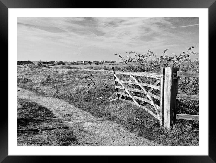 A view through a farm gate in black and white at Two Tree Island, with Hadleigh Castle on the horizon. Essex, UK.  Framed Mounted Print by Peter Bolton