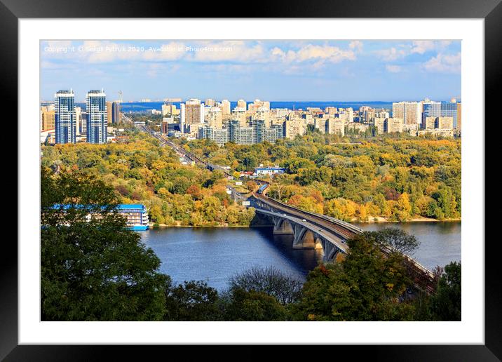Landscape of the autumn city of Kyiv with a view of the Dnipro River, a branch and a subway bridge, Hydropark and the left bank of the Rusanovka district. Framed Mounted Print by Sergii Petruk