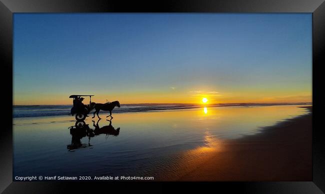 Silhouetted horse-drawn carriage beach sunset 1 Framed Print by Hanif Setiawan