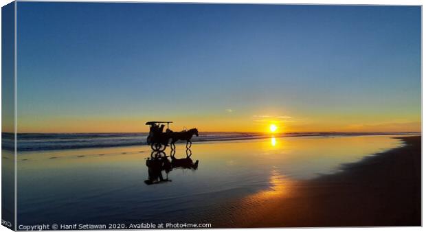 Silhouetted horse-drawn carriage beach sunset 1 Canvas Print by Hanif Setiawan