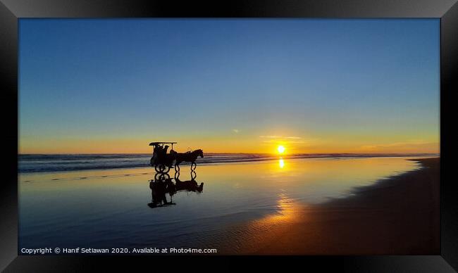 Silhouetted horse-drawn carriage beach sunset 1 Framed Print by Hanif Setiawan