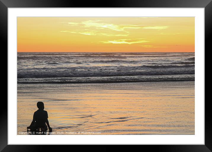 A young boy on wet sand beach at sunset. Framed Mounted Print by Hanif Setiawan