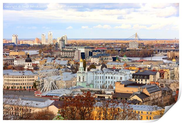 The landscape of the autumn city of Kyiv overlooking the old district of Podil with a Ferris wheel and a bell tower with a gilded dome, the Dnipro River and many bridges. Print by Sergii Petruk
