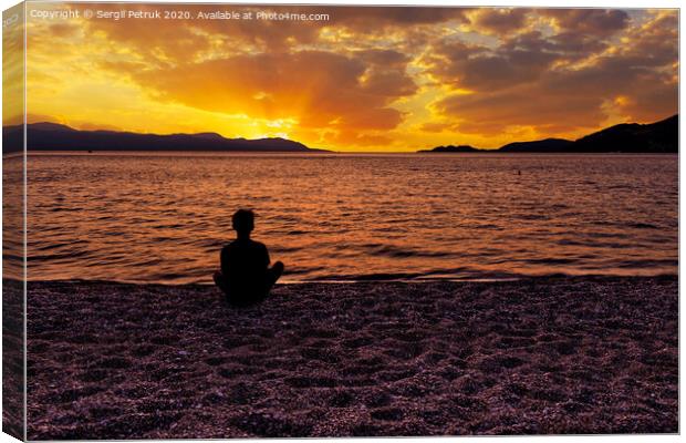Silhouette of a teenager who sits on a pebble sea shore and watches a beautiful, vibrant sunset on the Gulf of Corinth in Greece. Canvas Print by Sergii Petruk