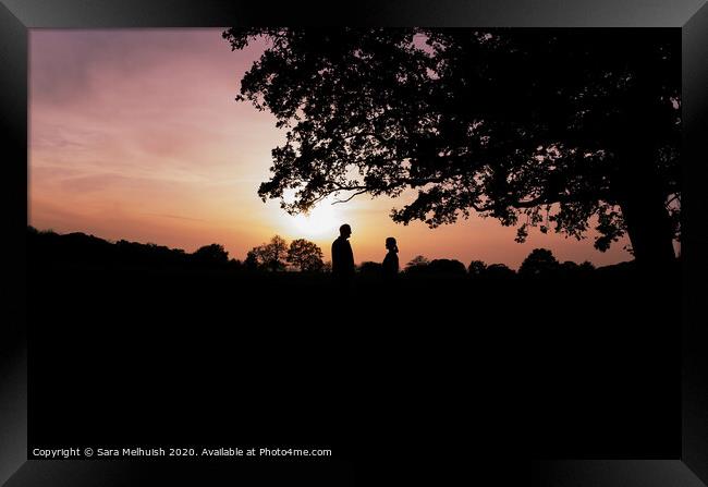 Two people standing under a tree in front of a sunset Framed Print by Sara Melhuish