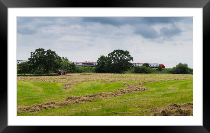 A Virgin train passes a tractor on a field Framed Mounted Print by Jason Wells