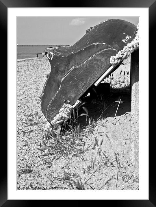 A wooden dinghy propped up against a seawall at Thorpe Bay, Essex, UK.  Framed Mounted Print by Peter Bolton