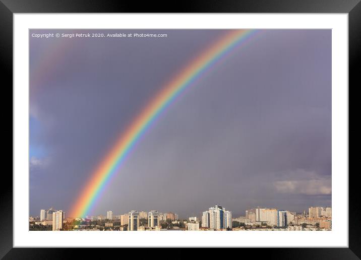 A large bright rainbow in the gray sky above the city after the last thunderstorm. Framed Mounted Print by Sergii Petruk