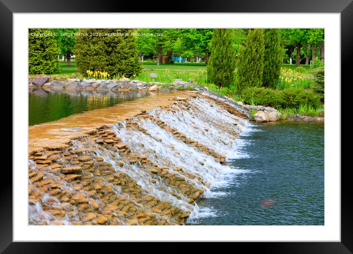 The waters of a beautiful decorative waterfall flow rapidly in a summer park. Framed Mounted Print by Sergii Petruk