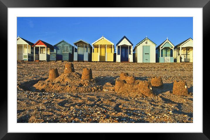 A row of beach huts at Thorpe Bay, Essex, UK, with sandcastles on the beach in the foreground. Framed Mounted Print by Peter Bolton