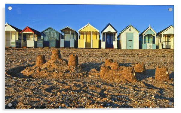 A row of beach huts at Thorpe Bay, Essex, UK, with sandcastles on the beach in the foreground. Acrylic by Peter Bolton
