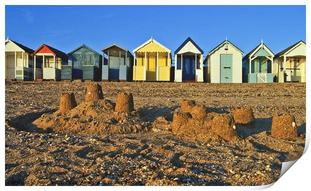 A row of beach huts at Thorpe Bay, Essex, UK, with sandcastles on the beach in the foreground. Print by Peter Bolton