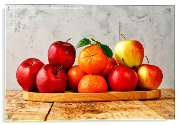 Red ripe apples and tangerines with green leaves lie on a wooden tray on an old wooden table with gray concrete background. Acrylic by Sergii Petruk