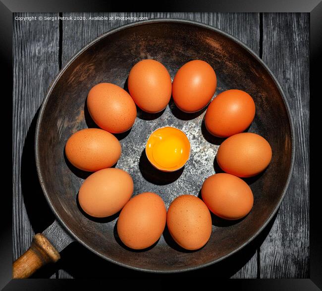 Brown chicken eggs in an old cast-iron frying pan look in the center at a broken egg with a bright yolk. Framed Print by Sergii Petruk