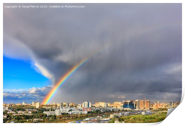 A bright rainbow in the sky above city houses after a thunderstorm separates thunderclouds from the clear sky. Print by Sergii Petruk