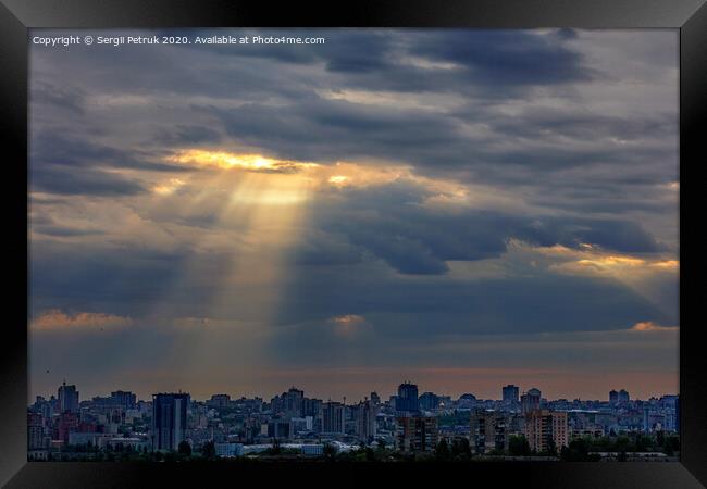 The sun's rays break through dense clouds at dawn over the city. Framed Print by Sergii Petruk
