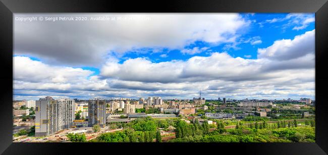Panorama of cityscape with big low clouds and bright sunlight. Framed Print by Sergii Petruk