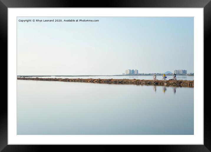 Reflections of 3 pedal bike riders shimmering over a lagoon near san pedro del pinatar in spain. Framed Mounted Print by Rhys Leonard