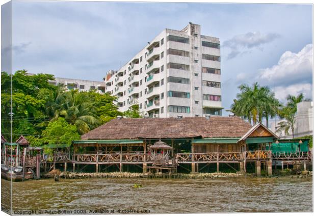 Traditional  house and modern apartment block on the Chao Phraya River, Bangkok, Thailand. Canvas Print by Peter Bolton