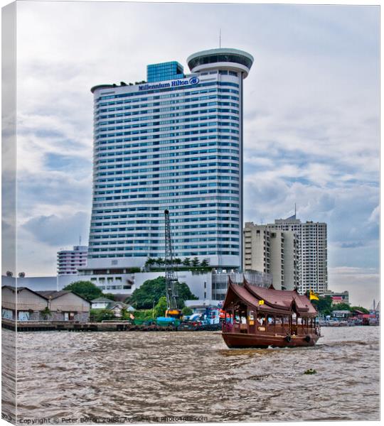 A tourist 'junk' on The Chao Phraya River passes the Millennium Hilton Hotel in Bangkok, Thailand. Canvas Print by Peter Bolton