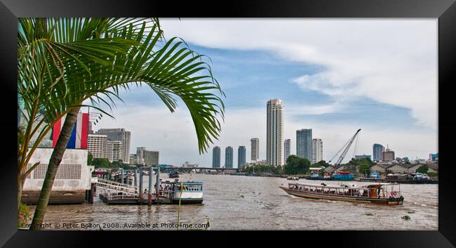 A view of ferries and landing stages on the Chao Phraya River, Bangkok, Thailand. Framed Print by Peter Bolton