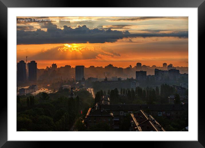 The sun's rays break through the rain clouds of a cloud at dawn and illuminate a sleeping city. Framed Mounted Print by Sergii Petruk